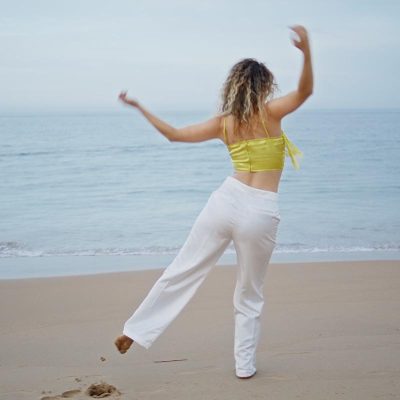 energetic girl dancing beach looking on beautiful ocean waves. w